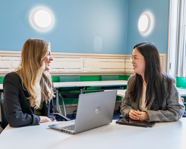 Two people meeting with a laptop between them.